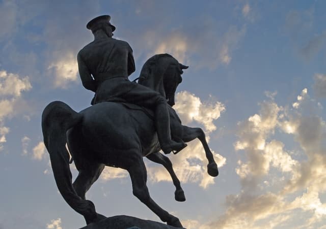 Silhouette of the Onur Anıtı statue of Atatürk on horseback against an evening sky